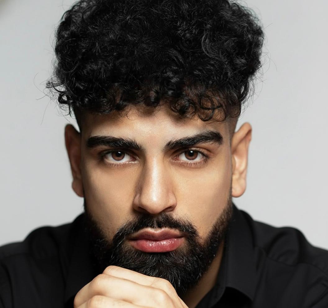 Portrait of a man with brown hair and glasses on a flat gray background.